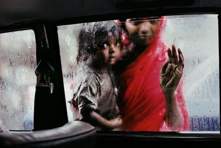 A mother and child beg for alms through a taxi window during the monsoon